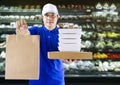 Food delivery service or shopping order online. Delivery man in blue uniform his hand holding paper box for take out food and bag Royalty Free Stock Photo