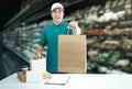 Food delivery service or shopping order online. Delivery man in green uniform his hand holding paper box for take out food and bag Royalty Free Stock Photo