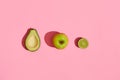 Food design. Composition of fresh fruits, avocado green apple and half of cutted avocado on pink coral background Royalty Free Stock Photo