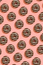 Food design with tasty chocolate glazed donut with white strips on coral peach pastel background top view pattern Royalty Free Stock Photo