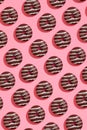 Food design with tasty chocolate glazed donut with white strips on coral pink pastel background top view pattern Royalty Free Stock Photo