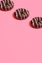 Food design with tasty chocolate glazed donut with white strips on coral pink pastel background top view pattern Royalty Free Stock Photo