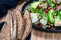 Healthy green vegetarian salad bowl lunch with avocado, artichokes, pomegranate seeds on dark plate. Royalty Free Stock Photo