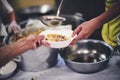 Food donation to the poor: The hands of the homeless are waiting to receive food from volunteers