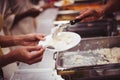 Food donation to the poor: The hands of the homeless are waiting to receive food from volunteers