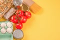 Food donations on yellow background with copy space - pasta, vegatables, canned food, cooking oil. Food bank and food