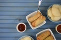 Food flat lay with vegetable spring rolls crackers and pots of dipping sauce with space