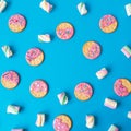 Food frame of cookies with pink glaze and marshmallow on blue background. Flat lay. top view. Royalty Free Stock Photo