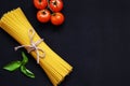 Food frame. Pasta ingredients. Cherry-tomatoes, spaghetti pasta, garlic, basil, parmesan and spices on dark background, copy Royalty Free Stock Photo