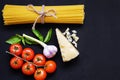 Food frame. Pasta ingredients. Cherry-tomatoes, spaghetti pasta, garlic, basil, parmesan and spices on dark background, copy Royalty Free Stock Photo