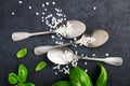 Food frame. Table silver vintage spoons, coarse sea salt, fresh basil on a dark background. Top view. A healthy balanced Royalty Free Stock Photo