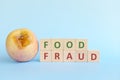 Food fraud concept. Rotten apple beside wooden blocks typography. Royalty Free Stock Photo