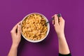 Food, healthy eating, people and diet concept - close up of woman eating muesli for breakfast over purple background Royalty Free Stock Photo