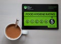 Food Hygiene Food Rating Sign, has a 5 rating very good. Close up of sign on white plate with knife and fork