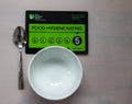 Food Hygiene Food Rating Sign, has a 5 rating very good. Close up of sign on white plate with knife and fork