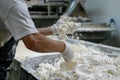 Food industry worker manipulating cheese curds with hands in gloves