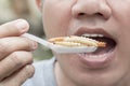 Food Insect: Man hand holding spoon eating Bamboo Worm insect or Bamboo Caterpillar deep-fried as food on white background, is Royalty Free Stock Photo