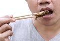 Food Insects: Man`s hand holding chopsticks eating Cricket insect deep-fried for eat as food snack on white background, it is goo