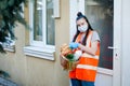 Teenagers deliver food to those in need. A young girl in a protective mask and medical gloves holds a basket of Royalty Free Stock Photo