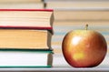 Food and knowledge of an apple, and next to a stack of hardcover books
