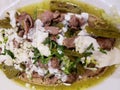 approach to dish with huarache of meat dipped in green sauce with cream, cheese and vegetables, typical mexican food Royalty Free Stock Photo