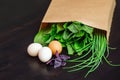 Food in a paper bag on a wooden table. Tomatoes, green onions, macaroni. Royalty Free Stock Photo