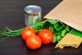 Food in a paper bag on a wooden table. Tomatoes, green onions, macaroni. Royalty Free Stock Photo