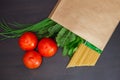 Food in a paper bag on a wooden table. Tomatoes, green onions, macaroni. Royalty Free Stock Photo