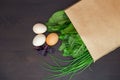 Food in a paper bag on a wooden table. Tomatoes, green onions, macaroni. Royalty Free Stock Photo