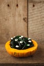 Food, party and holidays concept - plate pumpkin with gummy worms candies and eyes on wooden table, copy space