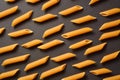 Food pattern of Raw Italian penne pasta pieces scattered on dark background Royalty Free Stock Photo