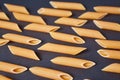 Food pattern of Raw Italian penne pasta pieces scattered on dark background Royalty Free Stock Photo