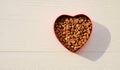 Food for pets in bowl of heart shape on wooden background with sunlight, top view, copy space Royalty Free Stock Photo