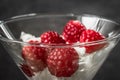 Raspberry with cream in a glass bowl close up