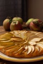 Close up view of apple pie made with slices of organic apples on ceramic craft plate with yellow stripe, linen napkin and fresh