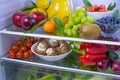 Food photography of a clean fridge filled with vegan foods such as fruits vegetables, juices and plant milk