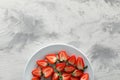 Food photography. Plate of delicious ripe strawberries on grey textured table, top view with space for text