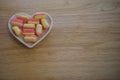 Food photography of sugar candy sweets flavored with rhubarb and custard in pink and yellow colors in a white love heart dish