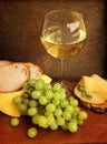 Food is a pleasure. Glass of a white wine, ripe white grapes, hard cheese sliced and white bread Royalty Free Stock Photo