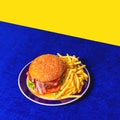 Food pop art photography. Delicious burger, hamburger, french fries on bright blue tablecloth isolated on yellow Royalty Free Stock Photo