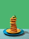 Food pop art photography. Delicious sweet pancakes with maple syrup and batter on plates over green background. Vintage
