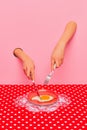 Food pop art photography. Female hand sticking out pink paper and cutting fried eggs on plate on retro tablecloth Royalty Free Stock Photo