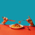 Food pop art photography. Female hands tasting spaghetti with meatballs on plaid tablecloth on bright blue