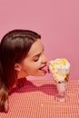 Portrait of young girl eating ice cream cocktail with corn isolated over pink background. Extraordinary taste Royalty Free Stock Photo