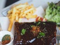 Food pork ribs grilled with BBQ sauce and caramelized in honey with French fries snack on wooden plate Royalty Free Stock Photo