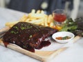Food pork ribs grilled with BBQ sauce and caramelized in honey with French fries snack on wooden plate Royalty Free Stock Photo
