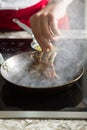 Food preparation chef cook in kitchen with pan over stove doing flambe crazy chef cooking with lamb Royalty Free Stock Photo