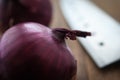 Food preparation, cooking concept: fresh raw red onions, knife on a rustic wooden cutting board background Royalty Free Stock Photo