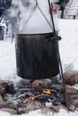 Food preparation in huge black bowl on bonfire in winter time Royalty Free Stock Photo