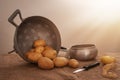 Food preparation, peeled potatoes in farmhouse rustic setting still life with saucepan, collander, knife, hessian aka Royalty Free Stock Photo